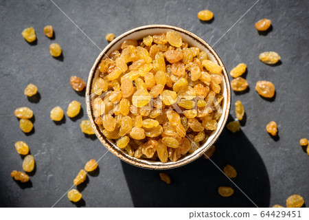 Golden raisins in bowl 64429451