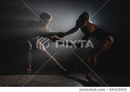 Beautiful young acrobats or gymnasts on floodlights background. Professional ballet couple dancing Beautiful young acrobats or gymnasts on floodlights background. Professional ballet couple dancing 64429983
