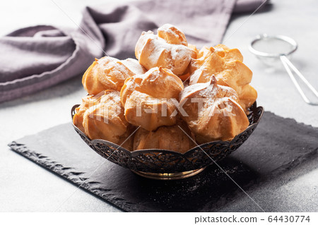 Profiteroles with custard and powdered sugar on a Profiteroles with custard and powdered sugar on a 64430774