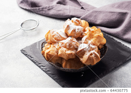 Profiteroles with custard and powdered sugar on a 64430775