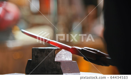 Making a knife out of hot metal using a pressure machine 64434583