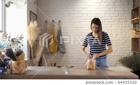 Woman gardener in flower shop make bouquet. 64435310