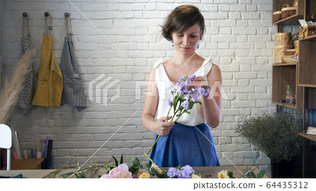 Woman gardener in flower shop make bouquet. Woman gardener in flower shop make bouquet. 64435312