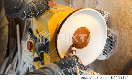 Carpenter paints wooden plate by brush. Carpenter paints wooden plate by brush. 64435315