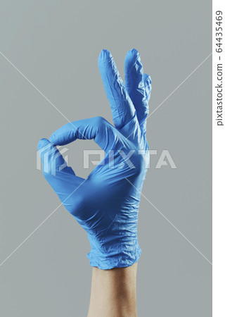 man wearing surgical gloves doing the OK sign 64435469