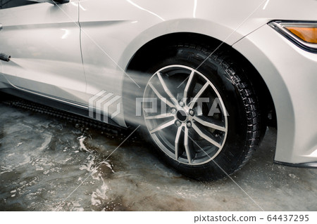 Washing a car by hand, car detailing. Close up image of the process of cleaning the car wheels with a water gun. Car rims wash using high pressure water. Detail of manual wheel cleaning concept. Washing a car by hand, car detailing. Close up image of the process of cleaning the car wheels with a water gun. Car rims wash using high pressure water. Detail of manual wheel cleaning concept. 64437295