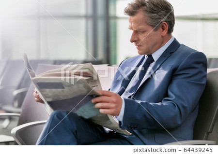 Mature businessman sitting and reading newspaper 64439245