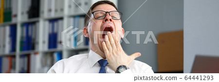 Tired businessman office sits at table and yawns 64441293