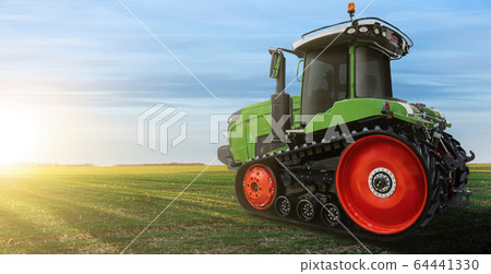 Rubber tracked agricultural tractor on a field. Rubber tracked agricultural tractor on a field. 64441330