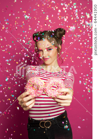 Woman with sweets in confetti on vivid pink 64441950