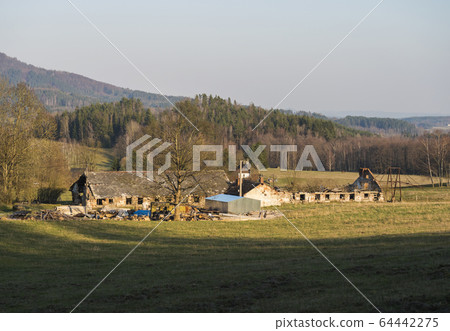 Old ruin of abandoned farm house at Lusatian mountains, early spring landscape with grass meadow, bare trees, forest, hills, clear blue sky background, golden hour light, horizontal, copy space Old ruin of abandoned farm house at Lusatian mountains, early spring landscape with grass meadow, bare trees, forest, hills, clear blue sky background, golden hour light, horizontal, copy space 64442275