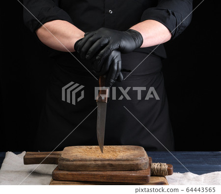 chef in a black shirt and black latex gloves holds 64443565