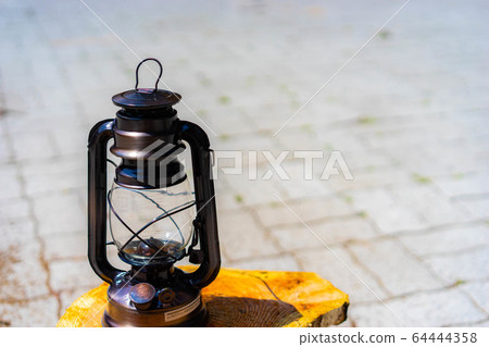 A Old Rustic Oil Lantern On A Wood Block At A Camping Site Stock