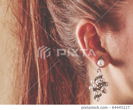 Tender girl ear with pearl earring. Human ear closeup 64445227