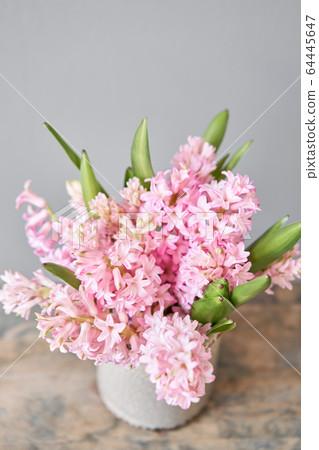 Bouquets of pink hyacinths in vase on wooden table. Spring flowers from Dutch gardener. Concept of a florist in a flower shop. Wallpaper. Bouquets of pink hyacinths in vase on wooden table. Spring flowers from Dutch gardener. Concept of a florist in a flower shop. Wallpaper. 64445647