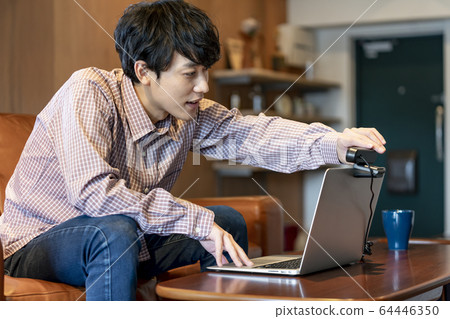 Telework image A young man setting a webcam 64446350
