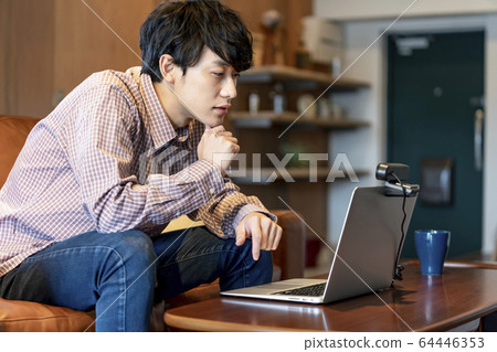 Young man speaking towards webcam 64446353