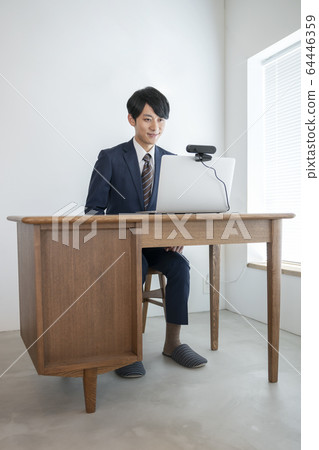 A young man heading for a laptop with a webcam A young man heading for a laptop with a webcam 64446359