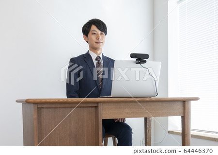 Image of a young man heading for a laptop with a webcam set for job hunting and web interview Image of a young man heading for a laptop with a webcam set for job hunting and web interview 64446370