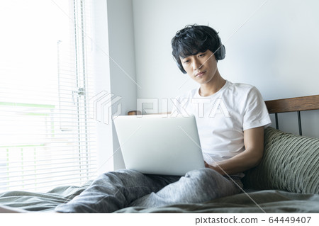 使用耳機操作個人計算機的年輕人 64449407