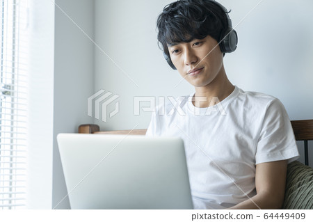 使用耳機操作個人計算機的年輕人 64449409