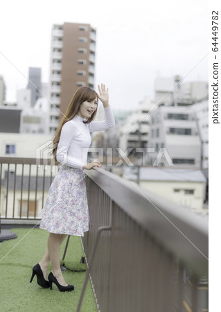 Woman waving from the roof of the building 64449782