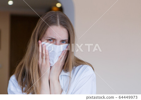 Portrait of a girl who covered her face with a mask. Frightened eyes of the patient. The concept of quarantine, self-isolation, protection from coronavirus, virus, fear of disease, treatment, medicine 64449973