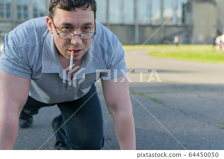 a man with a cigarette stands at the stadium in the start stand a man with a cigarette stands at the stadium in the start stand 64450050