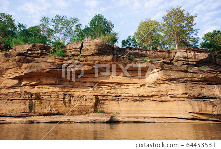 Yellow sandstone canyon cliff shoreline of Mekong river 64453531