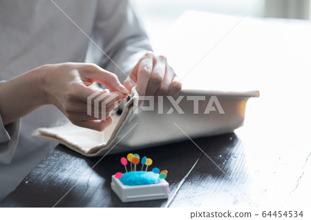 縫在房間裡一個年輕女子的手 縫在房間裡一個年輕女子的手 64454534