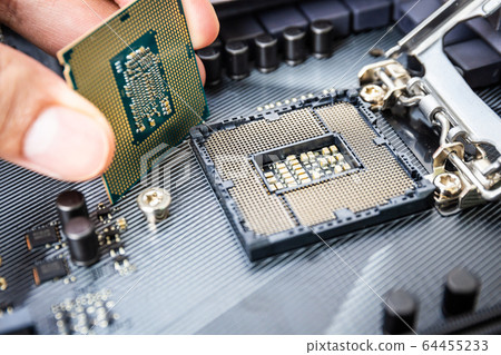 Closeup detail of CPU Chip over socket with hand of a modern computer black motherboard. Electronic small component details. Select focus 64455233
