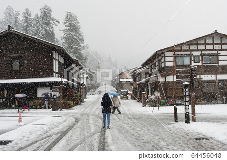 In the winter snow is heavy and the tourist walking on the street with Ancient houses background of Shirakawa-go village at Gifu, Japan. 64456048