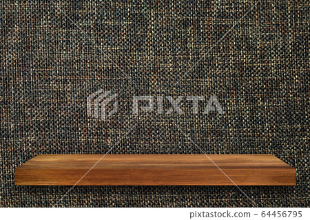 Empty top of wooden shelves on fabric wall 64456795