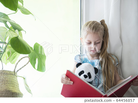 Sad child girl by the window 64456857