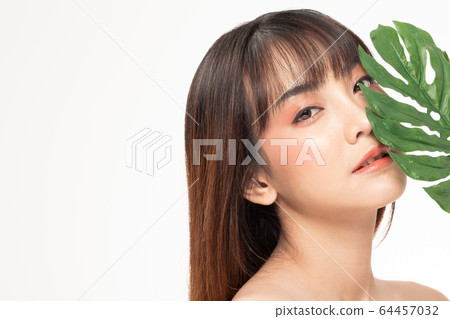 Beauty asian woman brown hair looking smile in camera happiness and holds a large green tropical leaf in hands and covers a part of her face and cheerful with make up brush,Beauty Concept. Beauty asian woman brown hair looking smile in camera happiness and holds a large green tropical leaf in hands and covers a part of her face and cheerful with make up brush,Beauty Concept. 64457032