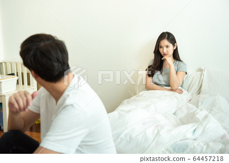 Asian man depresses and woman with unhappy relationship sit on bed after have an argument 64457218
