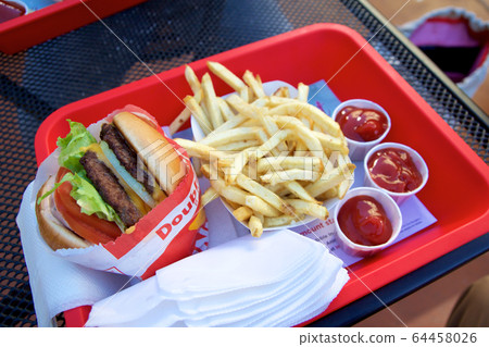 SAN FRANCISCO, CALIFORNIA, UNITED STATES - NOV 25th, 2018: In n Out Double Double cheeseburger with animal style, burger with protein style, and french fries in a tray 64458026