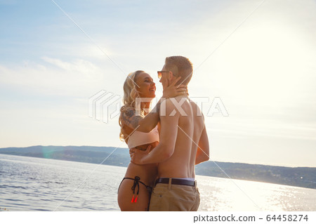 Happy laughing couple in love laughing at the beach against sun 64458274