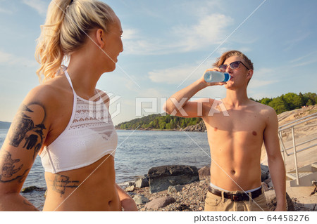 Close-up of young Woman Looking At Boyfriend Drinking Water 64458276