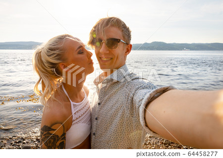 Happy Young Man Taking Selfie With Girlfriend At Beach 64458277