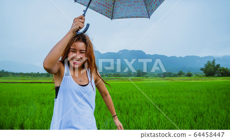 Asian women travel relax in the holiday. The women stood holds an umbrella in the rain happy Asian women travel relax in the holiday. The women stood holds an umbrella in the rain happy 64458447