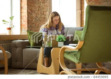 Young woman studying at home during online courses or free information by herself, making notes Young woman studying at home during online courses or free information by herself, making notes 64459995