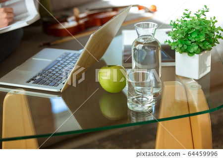 Young woman studying at home during online courses or free information by herself, focus on table Young woman studying at home during online courses or free information by herself, focus on table 64459996