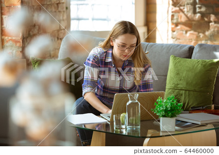 Young woman studying at home during online courses or free information by herself, making notes Young woman studying at home during online courses or free information by herself, making notes 64460000