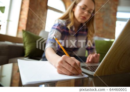 Young woman studying at home during online courses or free information by herself, making notes Young woman studying at home during online courses or free information by herself, making notes 64460001