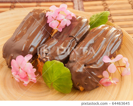 Eclair with chocolate custard decorated with pink flowers 64463645