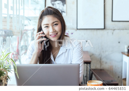 Beautiful Attractive Asian woman working with laptop smile and talking with customer in smartphone to get idea and requirement for success her job Beautiful Attractive Asian woman working with laptop smile and talking with customer in smartphone to get idea and requirement for success her job 64465831