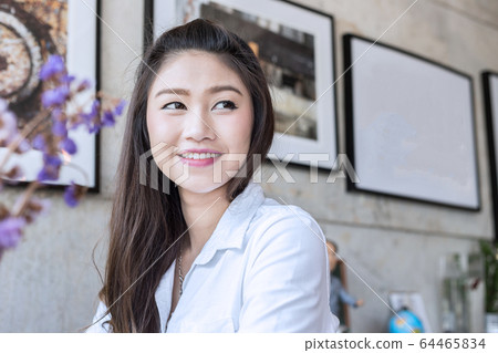 Beautiful young Asian woman smile and looking up and thinking in coffee shop cafe Beautiful young Asian woman smile and looking up and thinking in coffee shop cafe 64465834