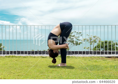 Happy Asian woman wearing black sport wear practice yoga Standing Forward Bend with beautiful sea view,Feeling relax and comfortable,Healthy Concept Happy Asian woman wearing black sport wear practice yoga Standing Forward Bend with beautiful sea view,Feeling relax and comfortable,Healthy Concept 64466020