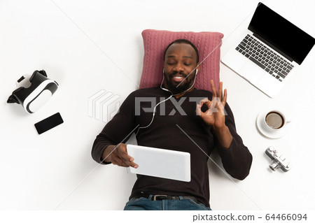 Emotional african-ameican man using gadgets isolated on white studio background, technologies connecting people. Online shopping, showing nice Emotional african-ameican man using gadgets isolated on white studio background, technologies connecting people. Online shopping, showing nice 64466094
